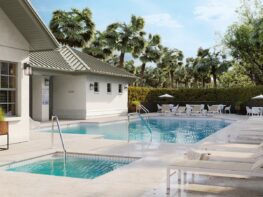 A pool area with loungers and palm trees.